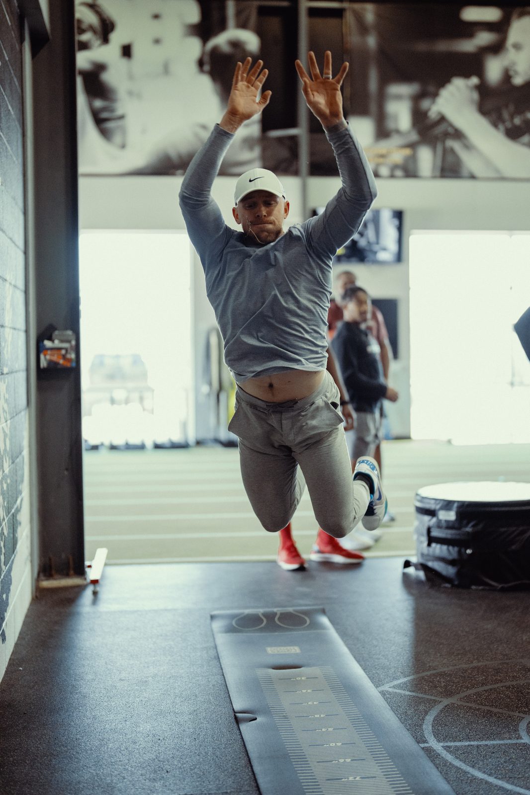 An athlete landing a standing broad jump on the measuring mat