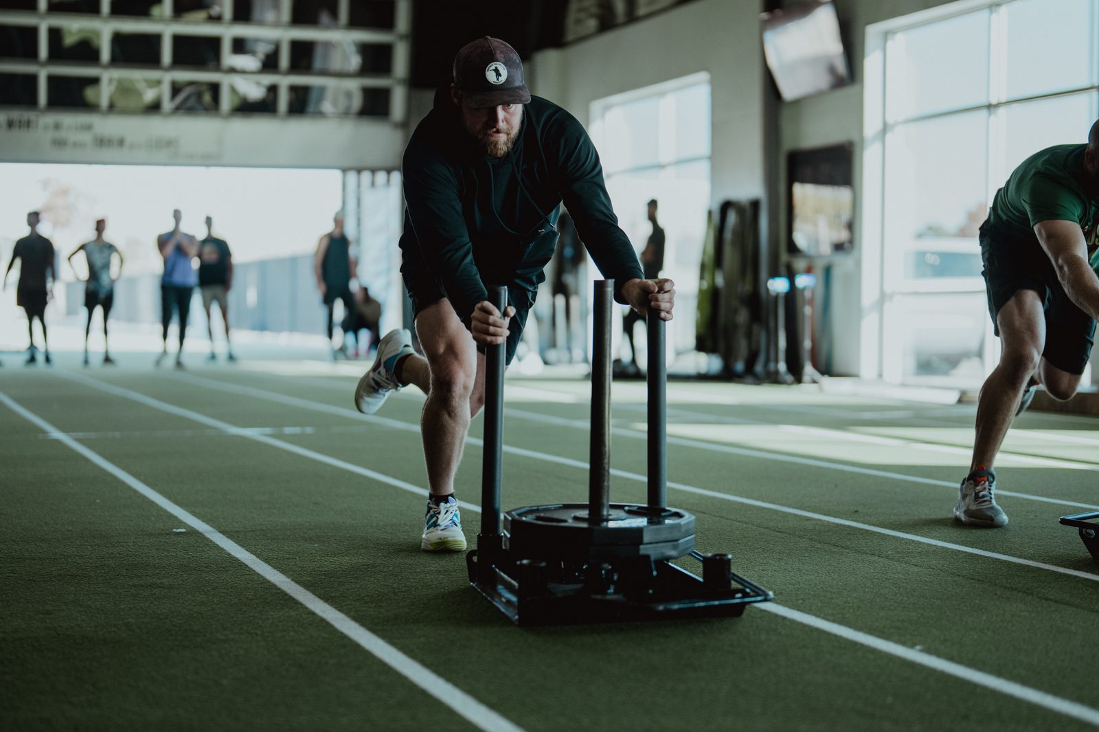 Two athletes racing weighted sleds on the APEC indoor track