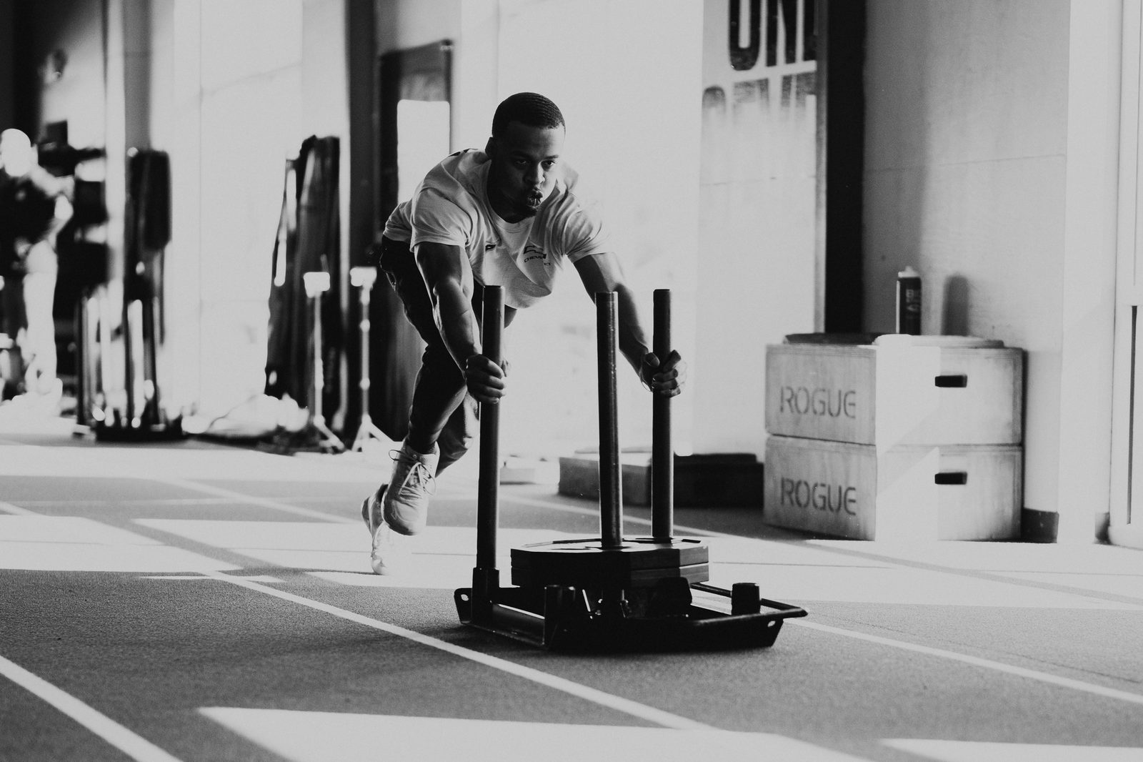 Athlete driving a weighted sled down the APEC turf